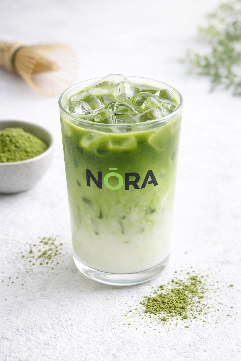 NŌRA branded iced matcha latte in a glass — part of the drinks menu